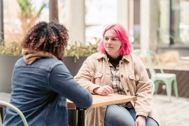 Two women listening and talking across a cafe table