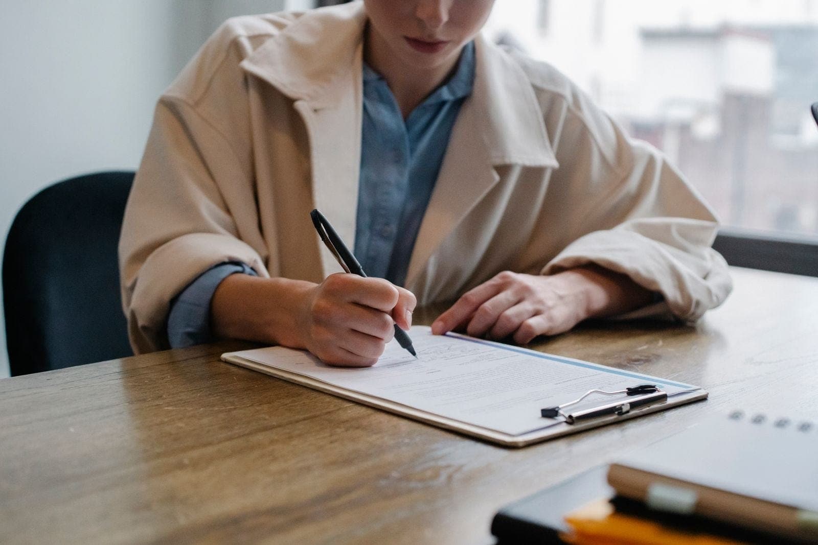 Hands writing notes on a clipboard during an office discussion